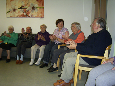Alte Menschen sitzen und klatschen im Stuhlkreis